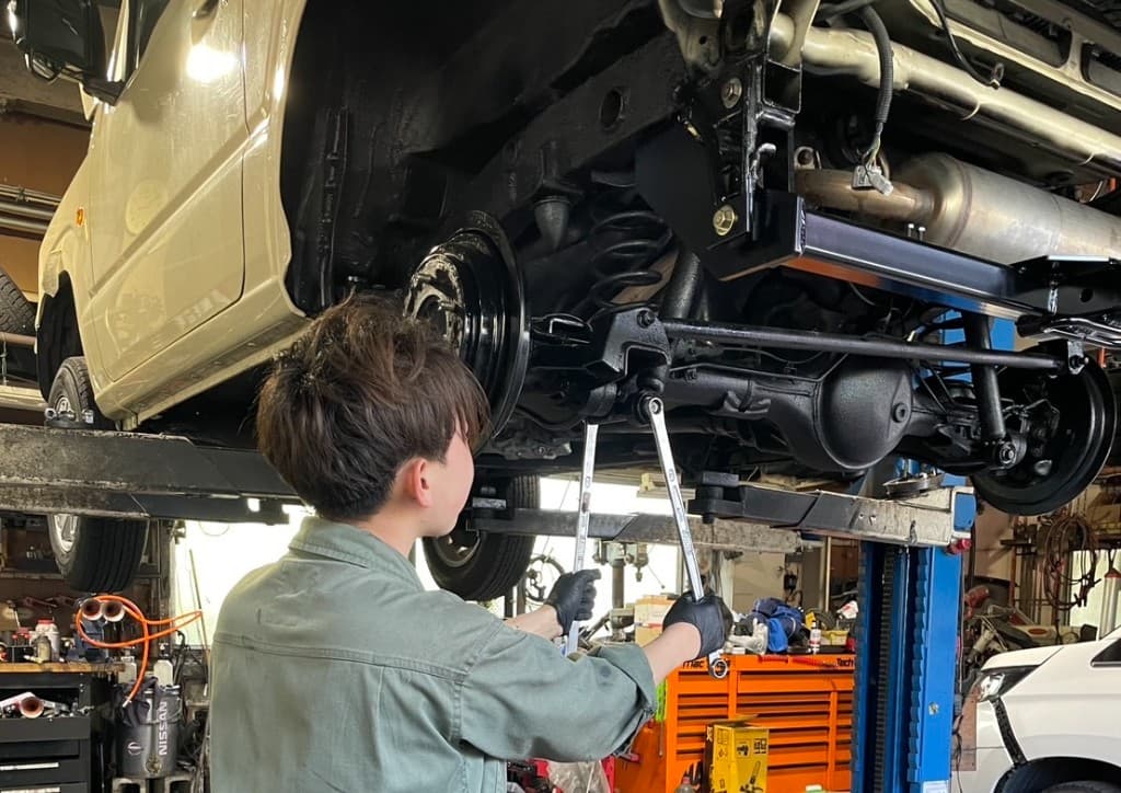 リフトに上げた車両の下で整備作業を行っている様子