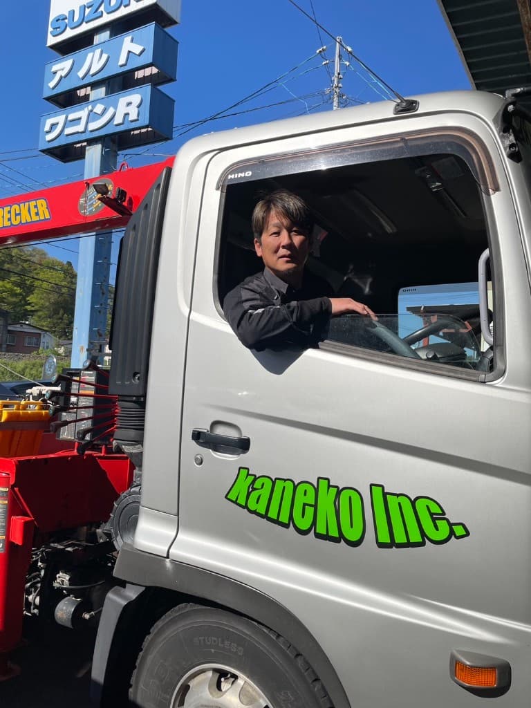 株式会社kanekoの車両搬送用トラックの運転席。ドアの社名ロゴと屋外の営業所周辺